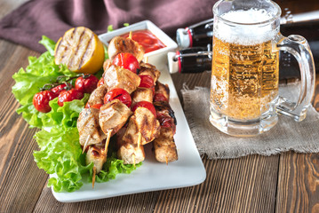 Grilled chicken skewers with mug of beer