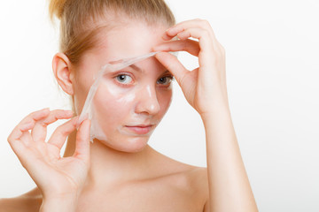 Woman removing facial peel off mask.