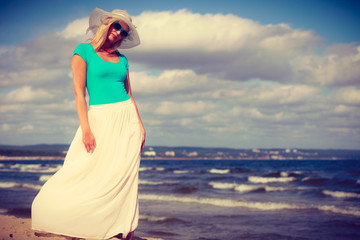 Fototapeta na wymiar Blonde woman wearing dress walking on beach