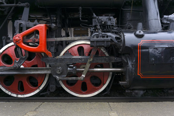 fragment of vintage functioning steam locomotive with leading wheels, piston and levers