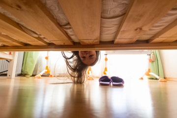 Portrait of teenage girl looking under the bed
