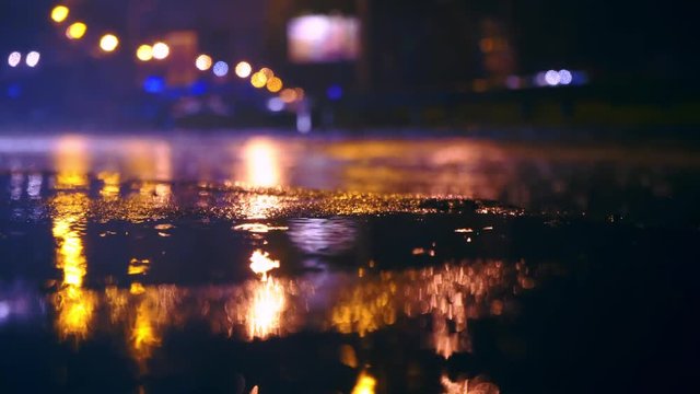 Cars drive into large puddles on the night road in the city, spray puddles scatter from under the wheels of the car