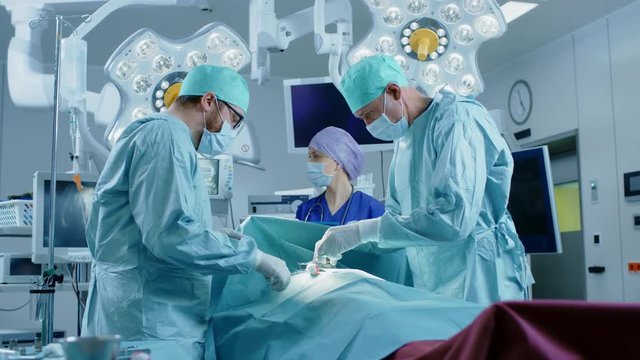 In the Hospital Operating Room Diverse Team of Professional Surgeons and Nurses Suture Wound after Successful Surgery.