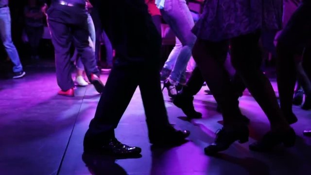 The feet of a boy and a girl dance close up. A girl in a skirt in heels and the guy dancing a fast dance. Party, night, dancers of Latin American dance. Close-up, indoors, artificial light, disco, nig