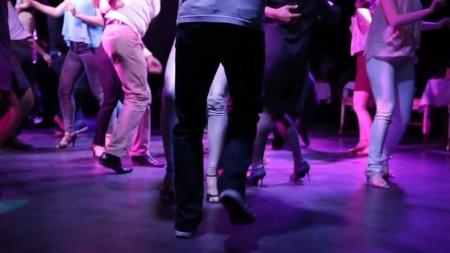 The feet of the boy and girl in the dance. Party, night, fast music, party Latin American dance. Close-up, night, indoors, artificial light, disco, night street fast dancing.