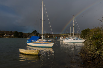 Boats in moody weather with rainbow in the background