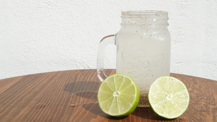 Agua fresca de limón con chia en frasco de vidrio sobre mesa de madera con fondo blanco