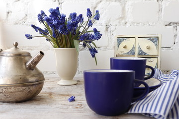 Serving breakfast. Blue cups, a teapot and a bouquet of muscari.