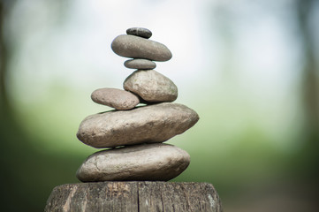 Fototapeta na wymiar closeup of stones balance on wooden fence on green blurred background