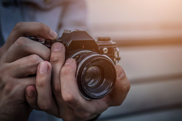 A man in a denim jacket with a vintage film camera at sunset
