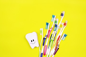 Toothbrushes and toy tooth on yellow background