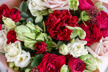 Bright red and white bouquet of beautiful flowers on wooden table. Floristry concept. Spring colors. the work of the florist at a flower shop. Vertical photo