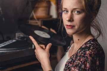 young woman putting on a vinyl record at home