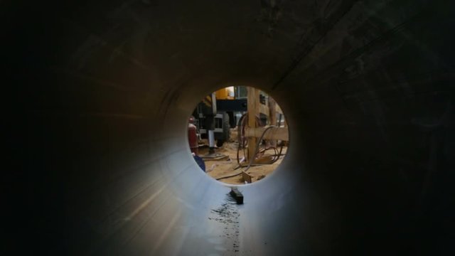 Huge plastic sewer pipe PEX, inside view, lying on the sand outside, on the street, on the site. Zoom out, dry season, summer, day, Sunny, natural light.