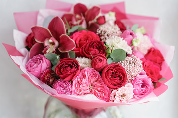 Bright red bouquet of beautiful flowers on wooden table. Floristry concept. Spring colors. the work of the florist at a flower shop. Vertical photo