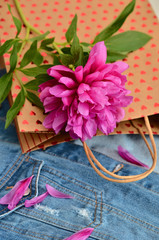 Still life. Pink peonies peony roses flower on gift craft with hearts over bag blue denim jacket, background. Garden spring flowers, Card Concept, copy space for text. mom's day, birthday, celebration