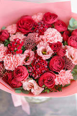 Bright red bouquet of beautiful flowers on wooden table. Floristry concept. Spring colors. the work of the florist at a flower shop. Vertical photo