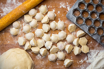 homemade dumplings on a table with flour and a dumplings shape on a wooden table