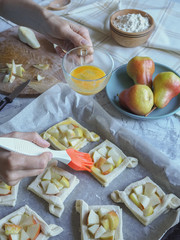 Pies of puff pastry with pears. The process of lubricating the dough with egg.