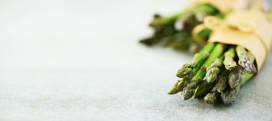 Fresh green asparagus in craft paper on marble background. Banner. Raw, vegan, vegetarian and clean...