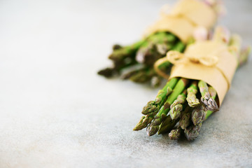 Fresh green asparagus in craft paper on marble background. Banner. Raw, vegan, vegetarian and clean...