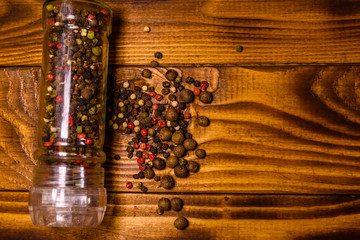 Obraz na płótnie Canvas Pepper mill and scattered spices on the wooden table. Top view
