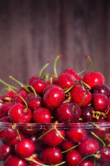 Sweet red cherries in glass bowl on dark wooden backgound with copy space. Summer and harvest concept. Vegan, vegetarian, raw food