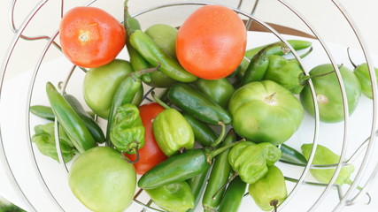 Chiles, chiles serranos, chiles habaneros, tomates y jitomtes frescos sobre mesa de madera con fondo blanco