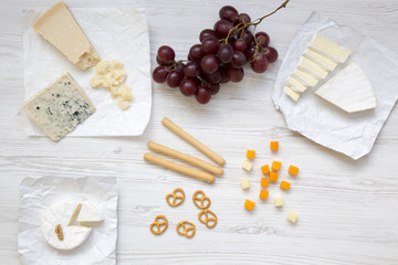 Tasting cheese with grapes, bread sticks, walnuts and pretzels on wooden background, top view. Food for romantic. Flat lay. From above.