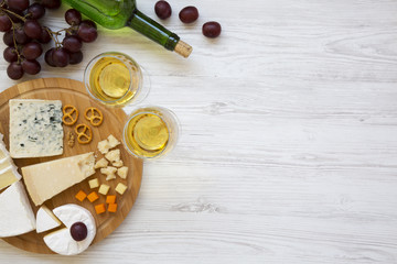 Tasting delicious cheese with wine, grapes, walnuts and pretzels on wooden background, top view. Food for romantic. From above. Flat lay. Copy space.
