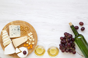 Tasting cheese with wine, grapes, walnuts and pretzels on wooden background. Food for romantic. From above. Top view. Flat lay. Copy space.
