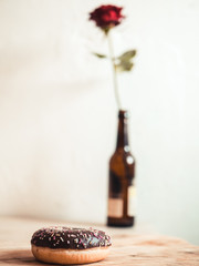 Donut on wooden board with red rose in background