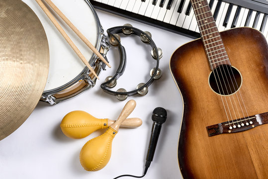 a group of musical instruments including a guitar, drum, keyboard, tambourine.