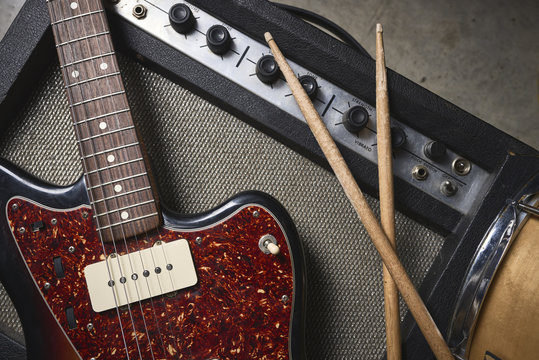 a group of musical instruments including an electric guitar, drum, cymbal, and amplifier