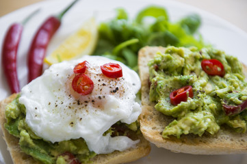 Close-up view of trendy avocado-chilli toast with poached egg. Shallow depth of field.