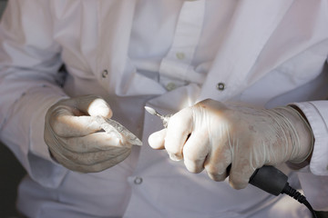 Dentist with latex gloves holding mouth guard in one hand and polish tool on another