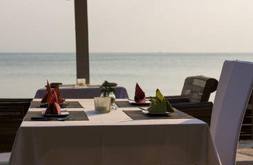 Nicely set up diner table with napkins on plates at restaurant by the sea in the island of Koh Phangan, Thailand