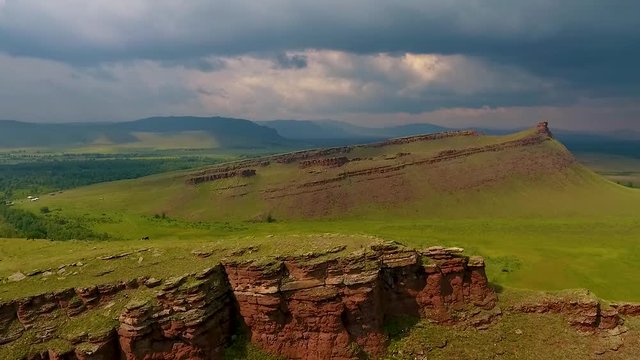 Aerial view of the mountain range Sunduki, green fields sky before the storm in the Republic of Khakassia. Russia