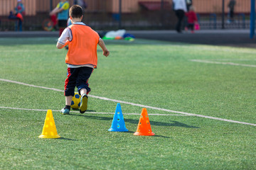 Obraz premium boys football players practice dribbling, kickson soccer training on the field in the summer