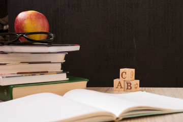 apple, book, glasses, cubes with letters on a black background