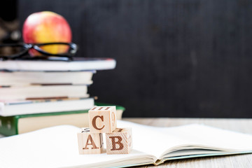 apple, book, glasses, cubes with letters on a black background