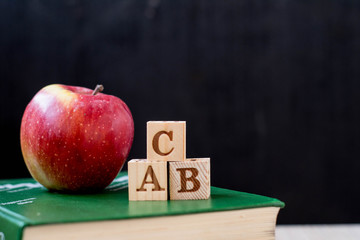 apple, book, glasses, cubes with letters on a black background