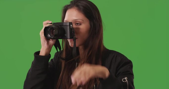 Portrait of female photographer using dslr camera to take picture on greenscreen