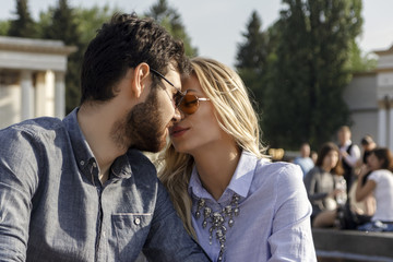 Fototapeta premium Young cute couple is kissing on the park background on a beautiful sunny summer day, close-up.