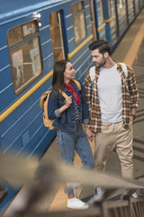 stylish travelers with backpacks at metro station