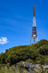 Mountain top communications tower in Costa Rica, painted aviation red and white and covered with antennas
