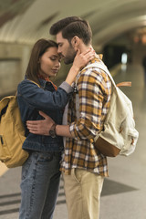 stylish couple of travelers embracing each other at subway station