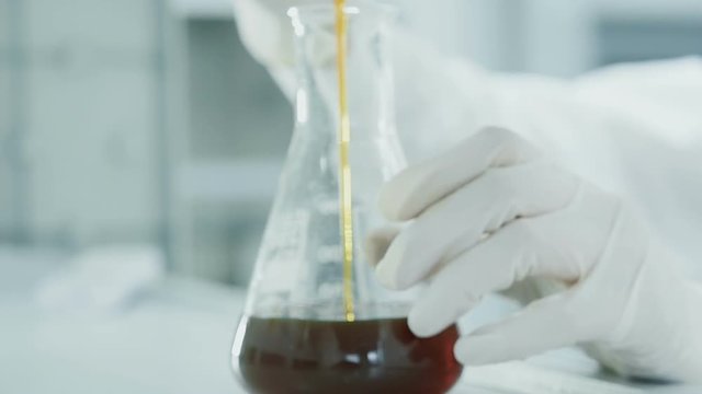 Laboratory concept, person close up dropping solute by measure to glass slow motion. The process of making cosmetic or scrutiny expertise of petrol. The scientist chemist testing the chemical material