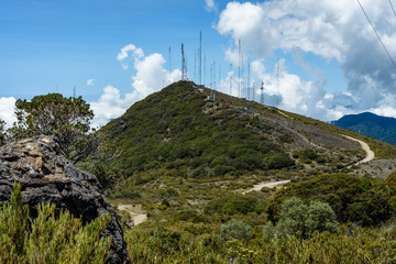 Fototapeta premium Mountain top landscape covered in communication towers and a dirt access road leading up to them 