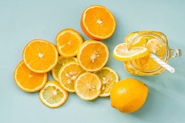 lemonade in a mason jar with a drinking straw decorated with slices of citrus oranges and lemons top view on blue background